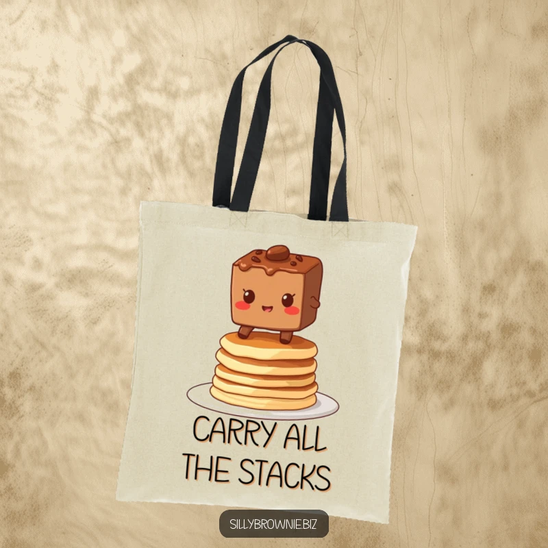 Funny tote bag showcasing a brownie character grinning while balancing on a stack of wobbly pancakes, perfect for carrying breakfast joy.